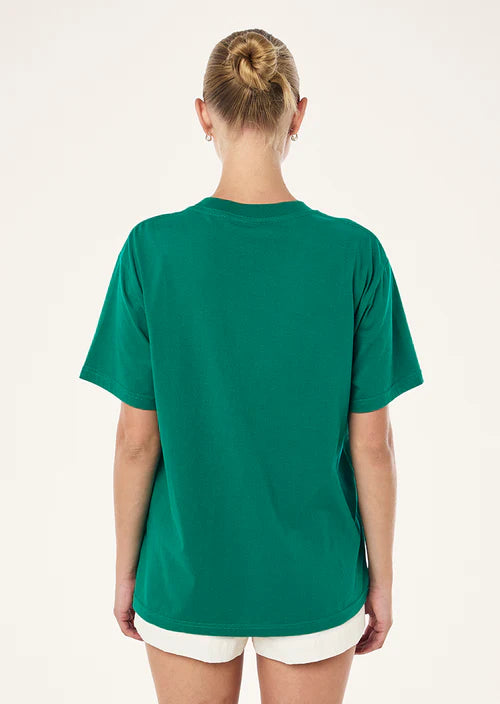 Person wearing a green t-shirt and white shorts on a plain background