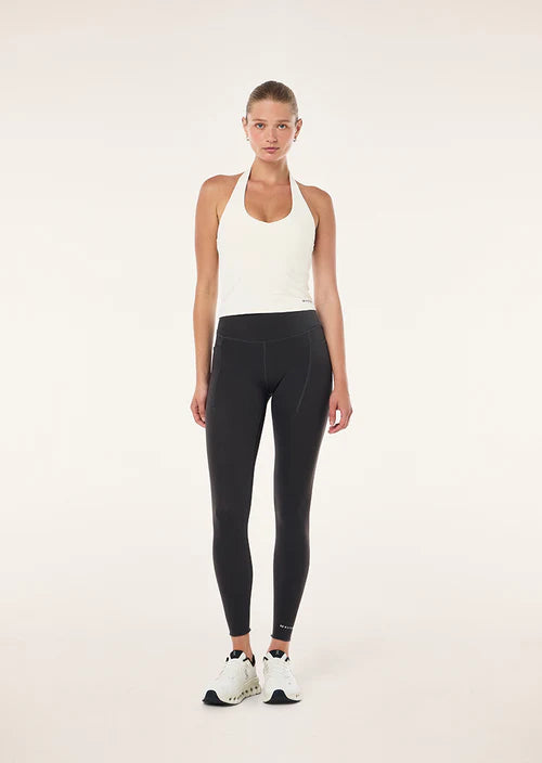 Woman wearing a white tank top and black leggings on a white background