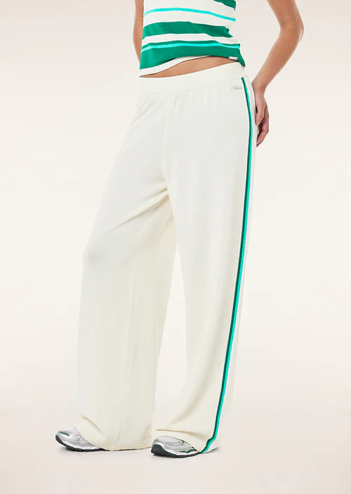 Person wearing white pants with a green stripe and a green and white striped top on a light background