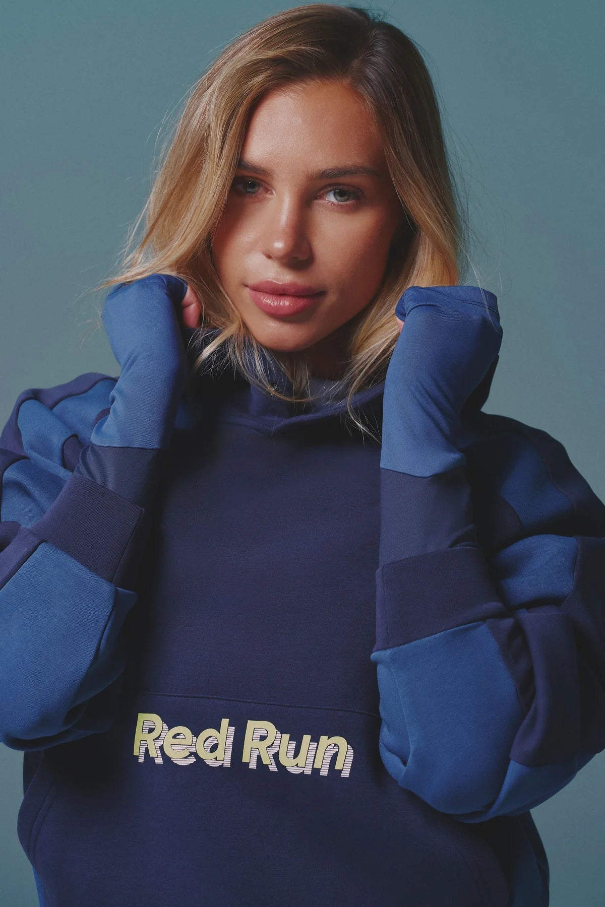 Person wearing a blue hoodie with 'Red Run' text against a teal background