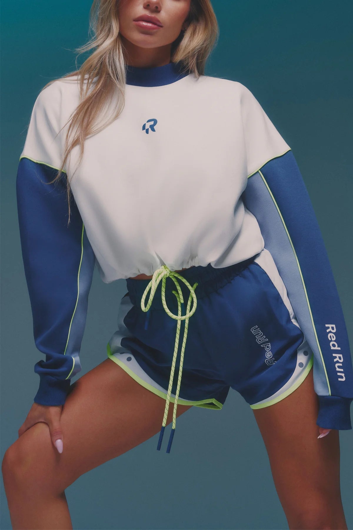 Person wearing a blue and white athletic outfit with a visible brand logo on a teal background
