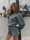 Woman wearing a green sweatshirt and shorts on a city street