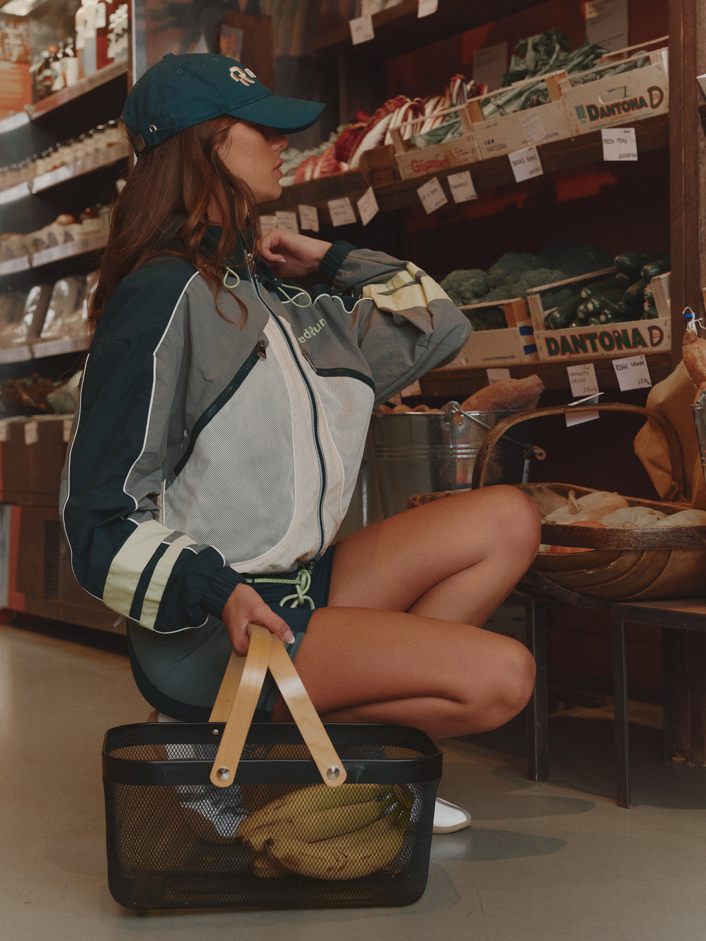 Person in a grocery store aisle with a bag, wearing a jacket and cap.