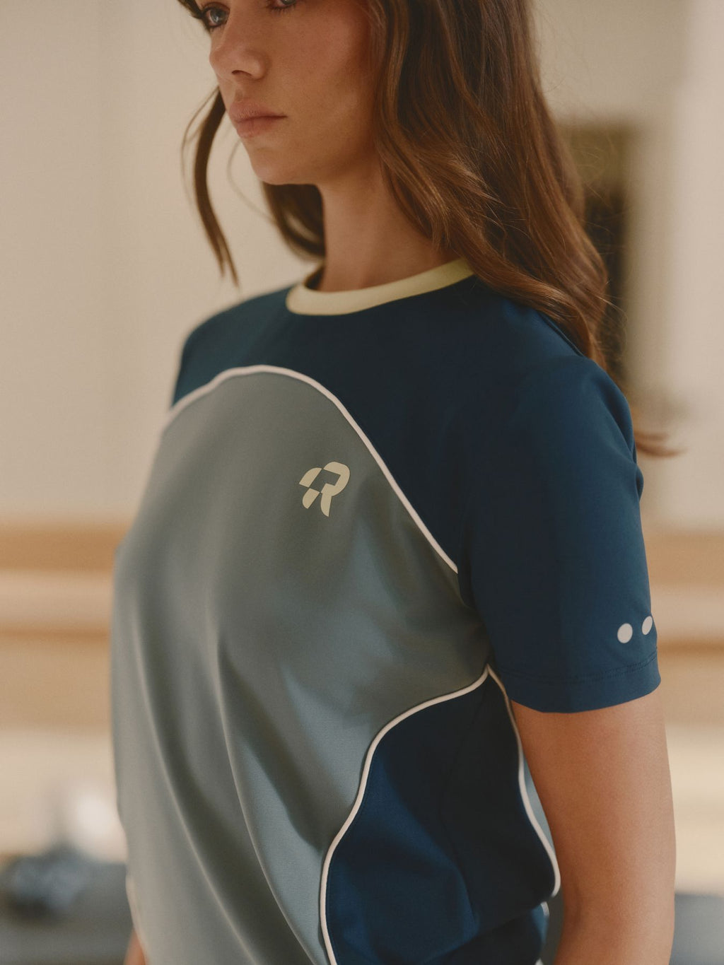 Person wearing a sports jersey with a logo on a blurred indoor background