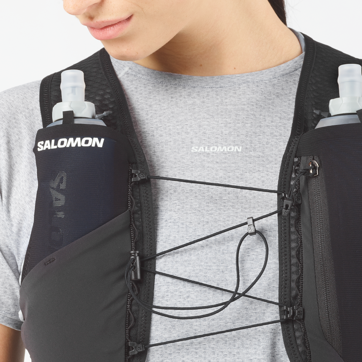 Person wearing a Salomon hydration vest with two water bottles on a plain background