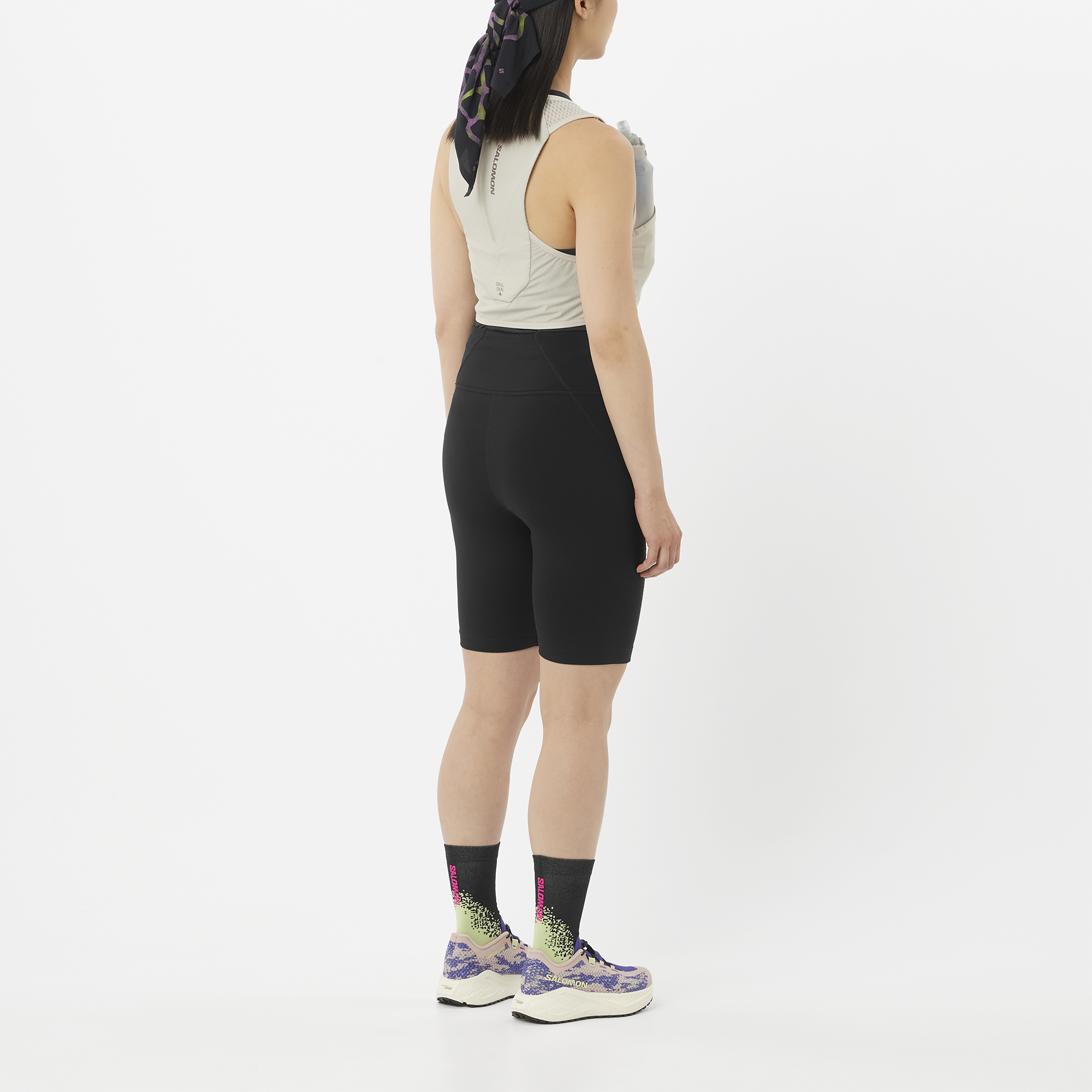 Person wearing black cycling shorts and a Salomon back pack in grey on a white background