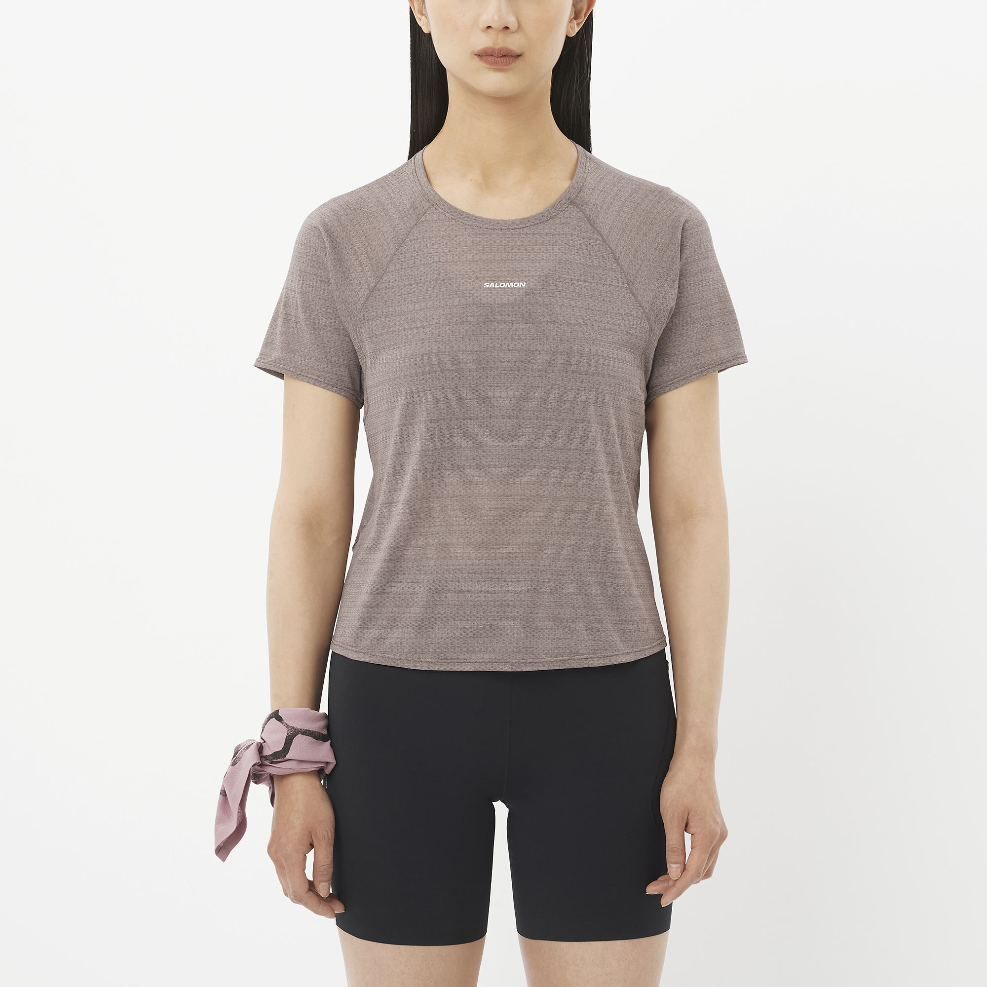 Woman wearing a gray athletic shirt and black shorts on a white background