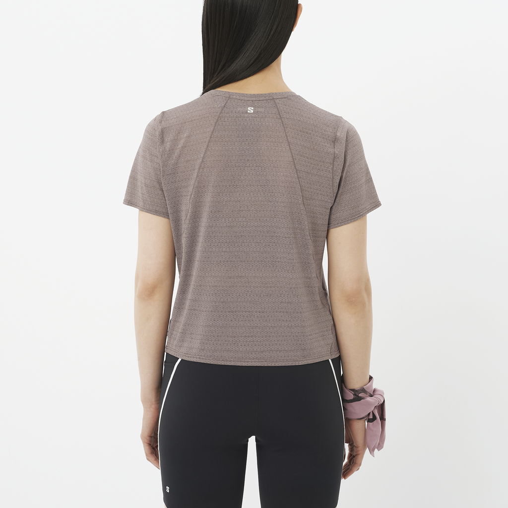Person wearing a brown athletic shirt and black leggings on a white background