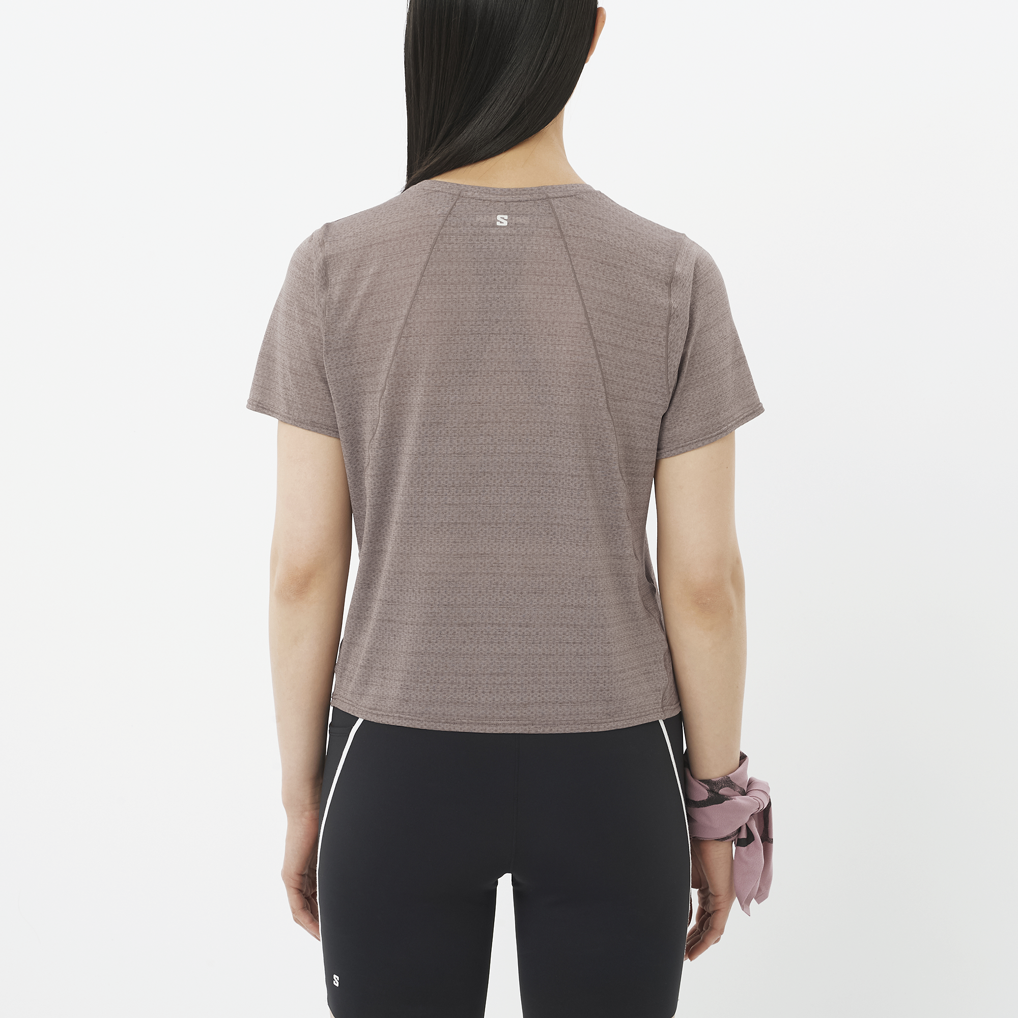 Person wearing a brown athletic shirt and black leggings on a white background