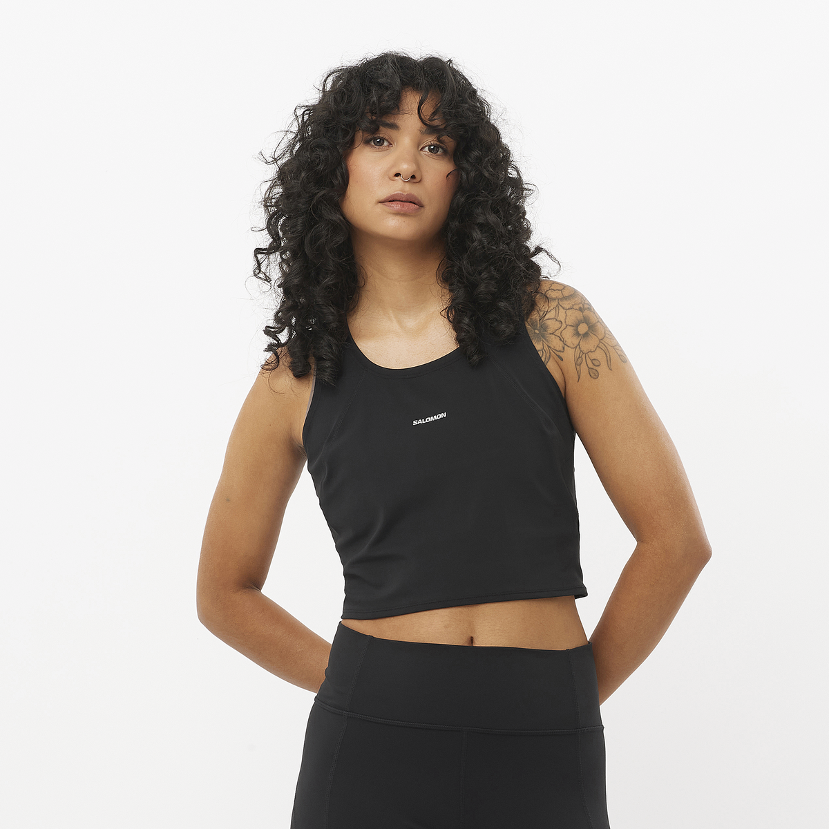 Woman wearing a black tank top with a brand logo on a white background