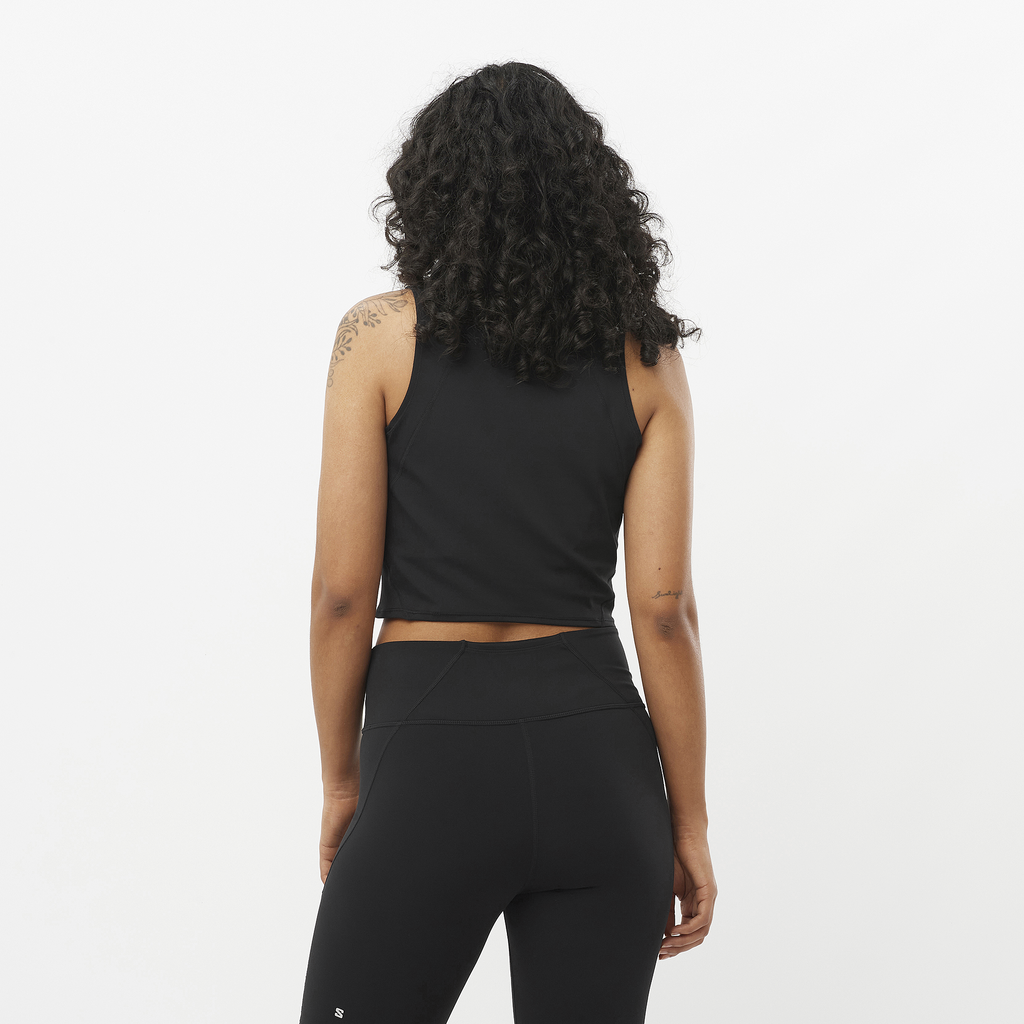 Person wearing a black sleeveless top and leggings on a white background