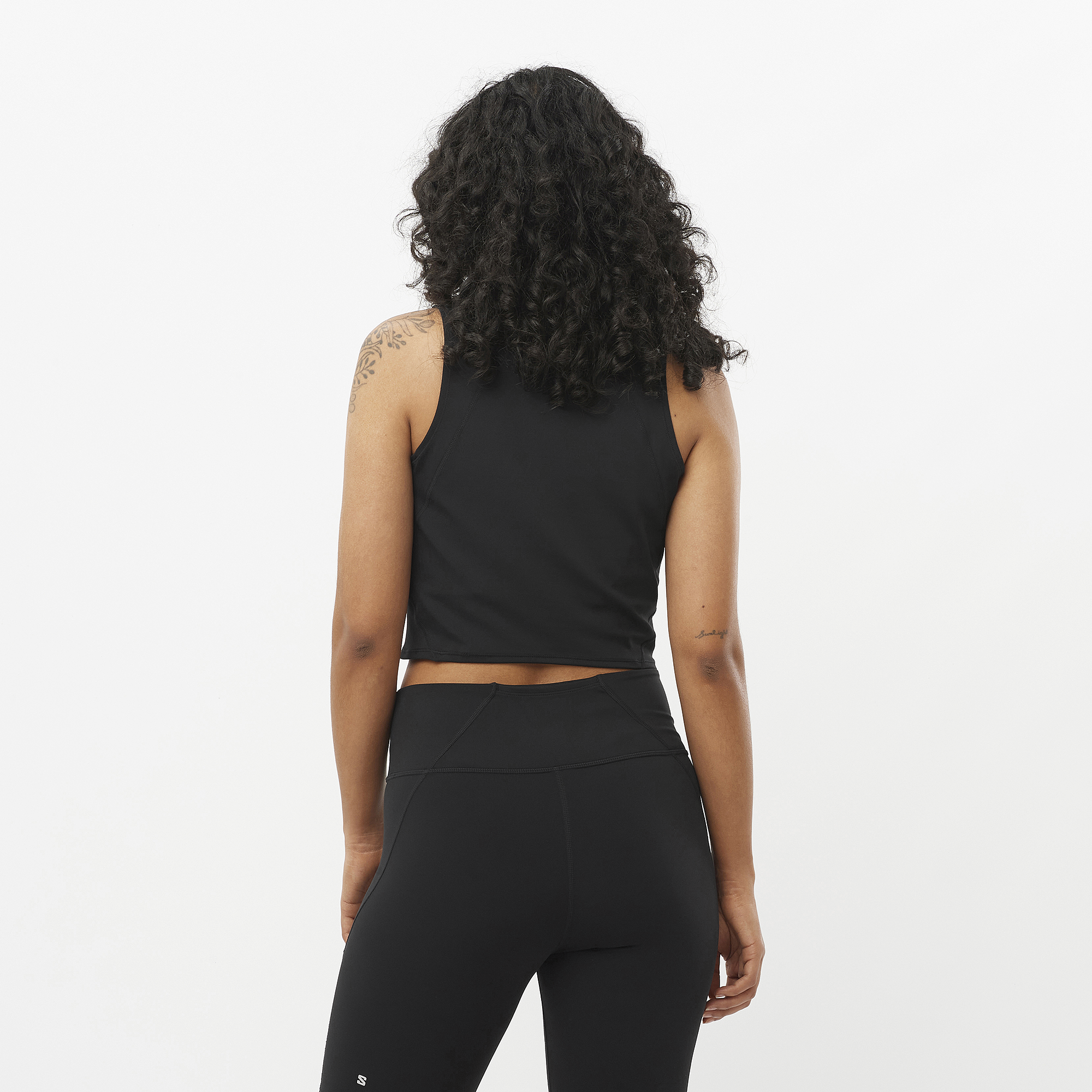 Person wearing a black sleeveless top and leggings on a white background