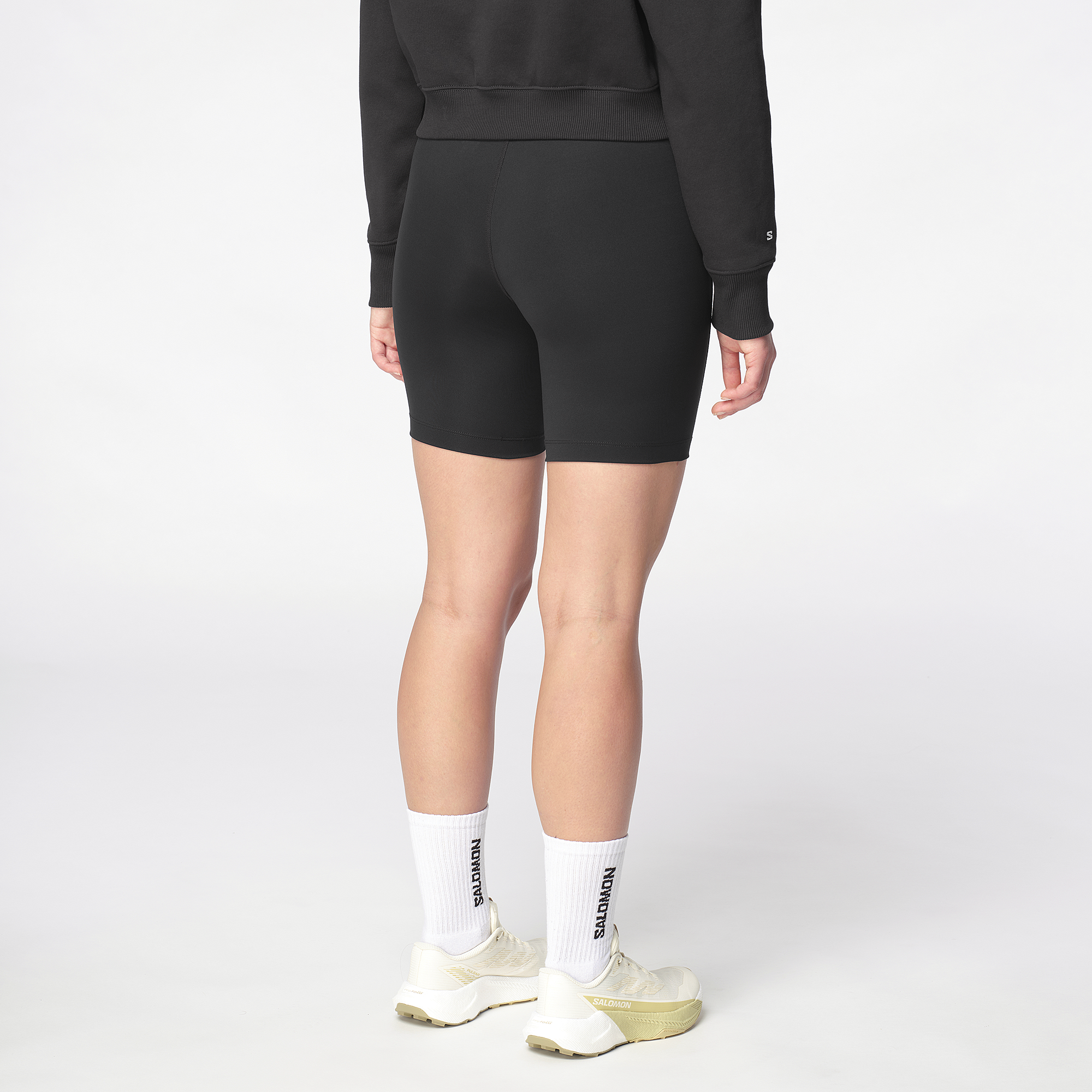 Person wearing black shorts and white socks on a white background