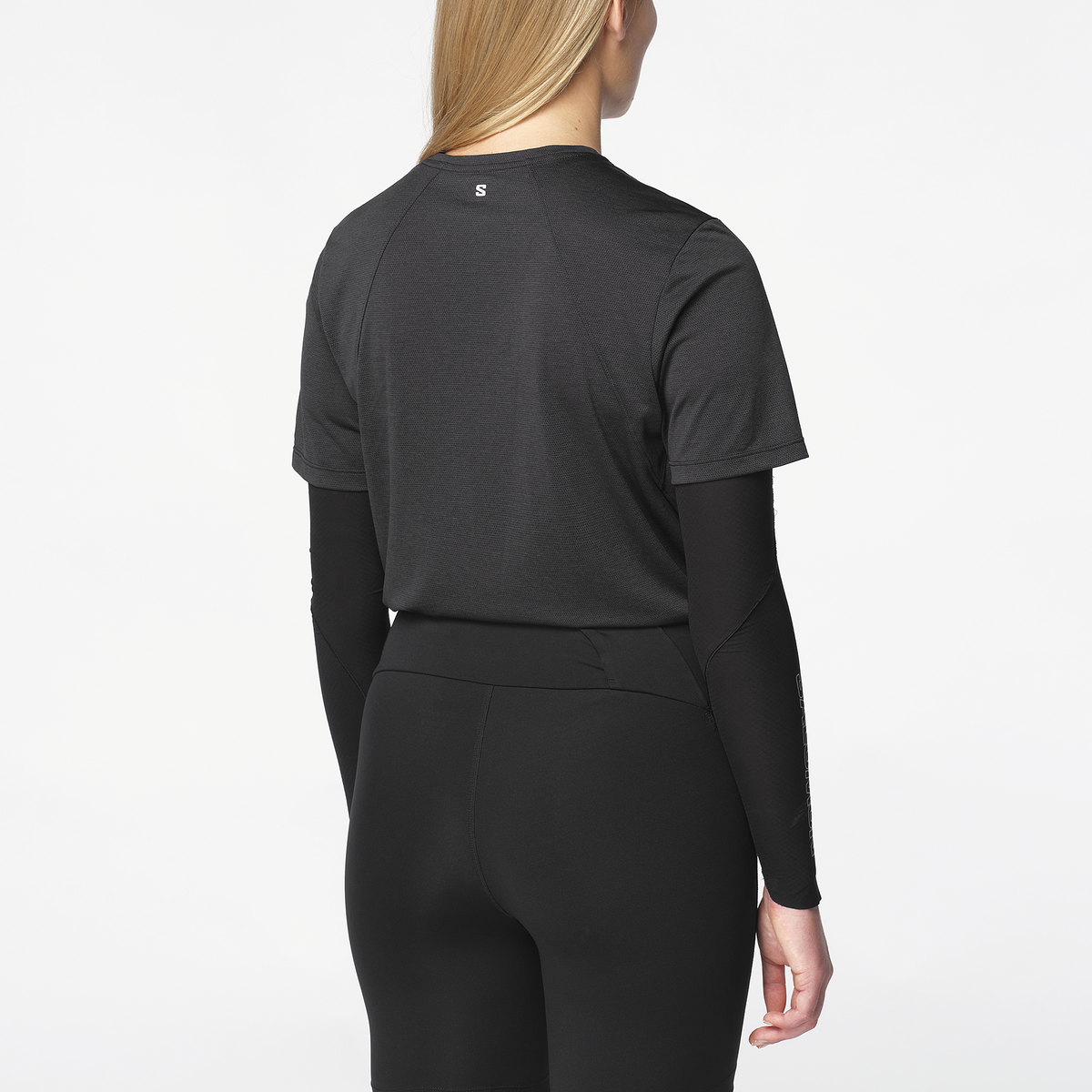 Person wearing a black long-sleeve athletic top and leggings on a white background