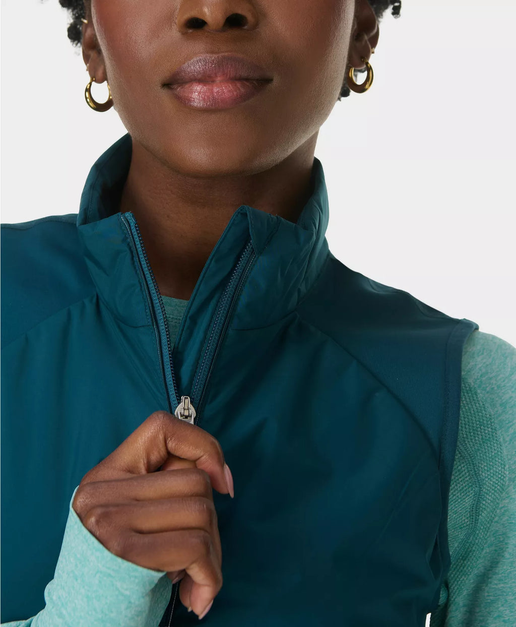 Person wearing a teal vest with a plain background