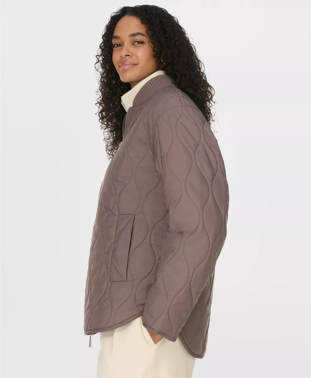 Woman wearing a brown cable quilted jacket on a white background