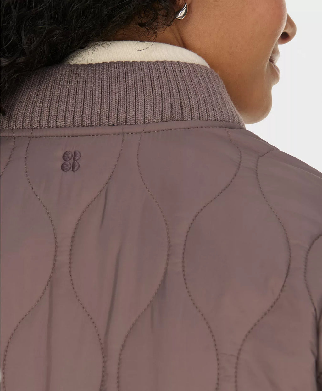 Close-up of a person wearing a brown quilted jacket with a white collar.