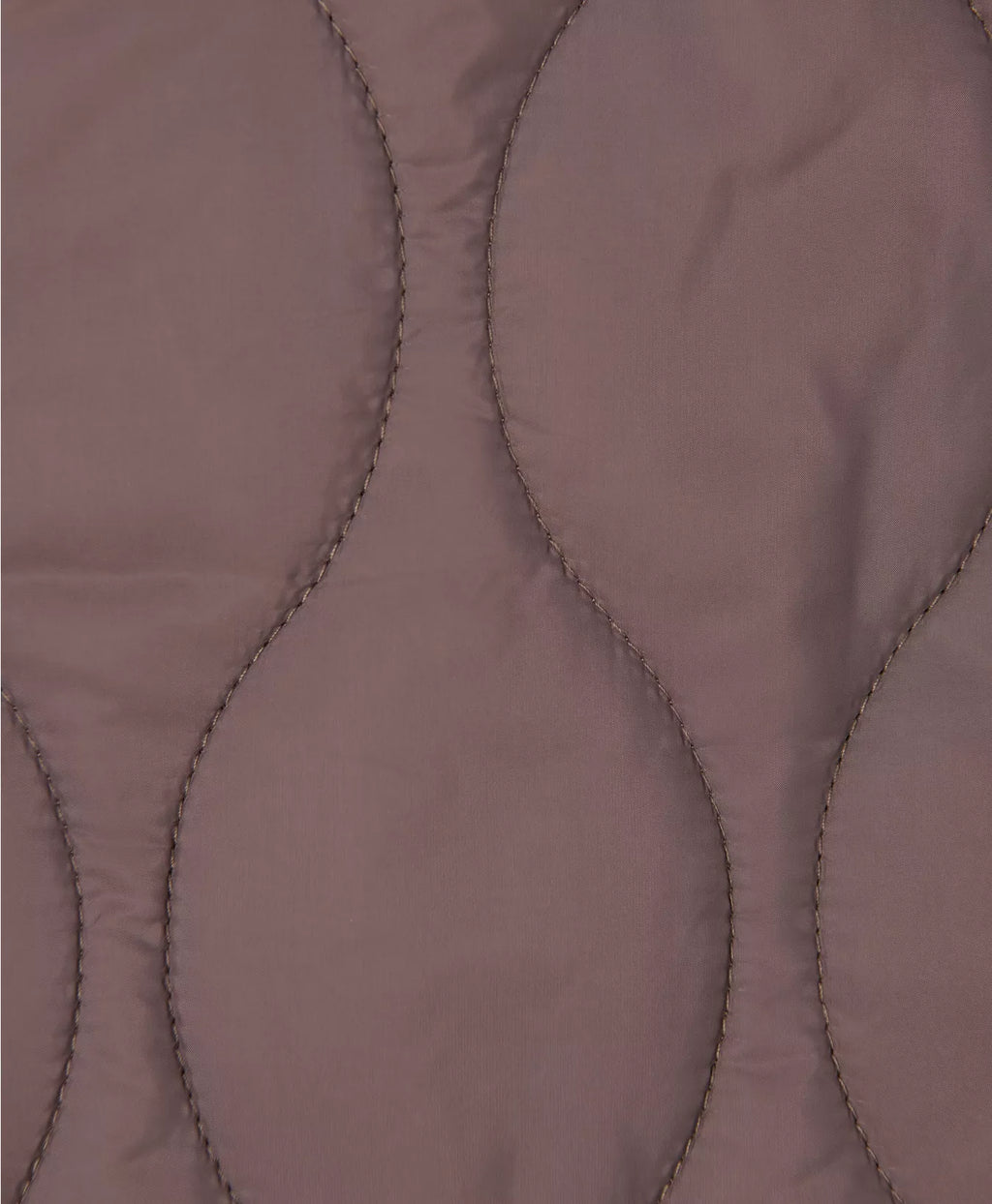 Close-up of a quilted fabric with a diamond pattern on a brown background