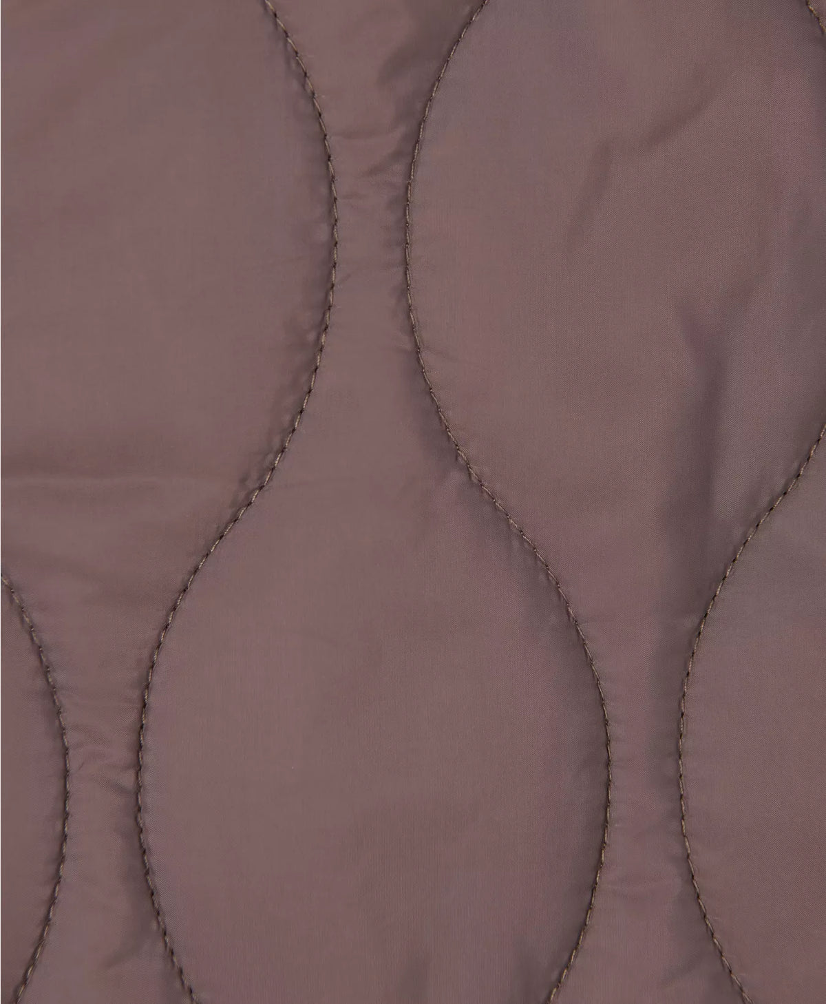 Close-up of a quilted fabric with a diamond pattern on a brown background