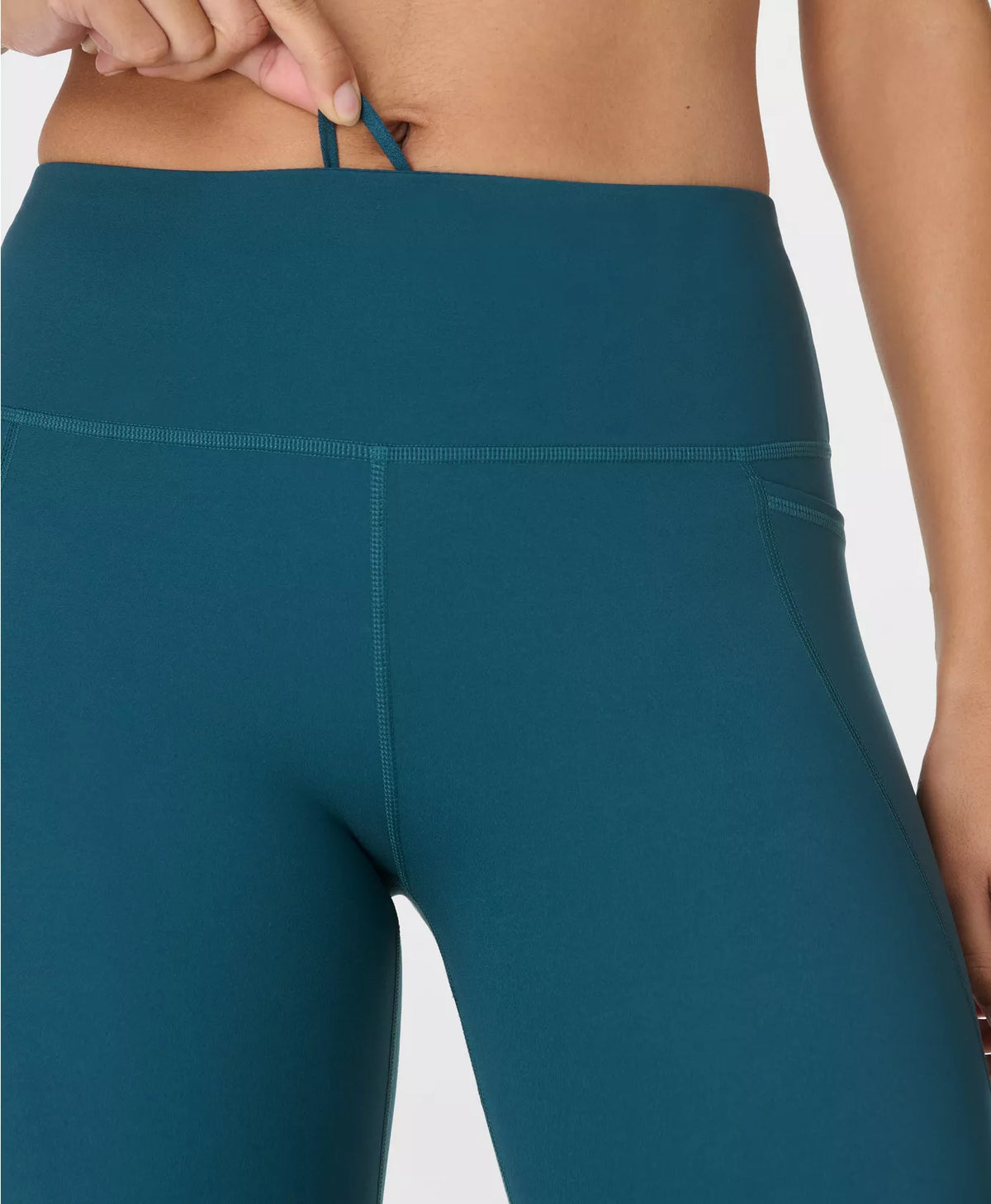 Teal leggings worn by a person on a white background