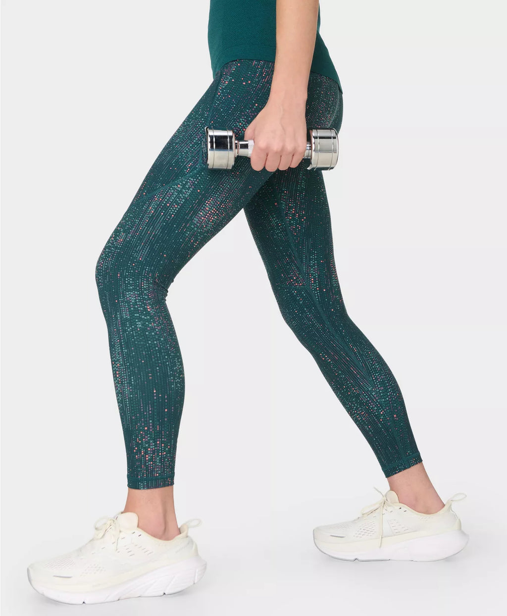 Person wearing green leggings holding a dumbbell on a white background
