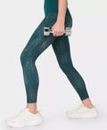 Person wearing green leggings holding a dumbbell on a white background