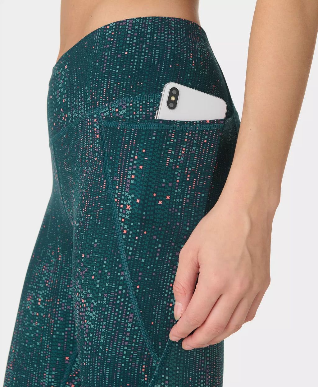 Green patterned leggings with a pocket holding a phone on a white background