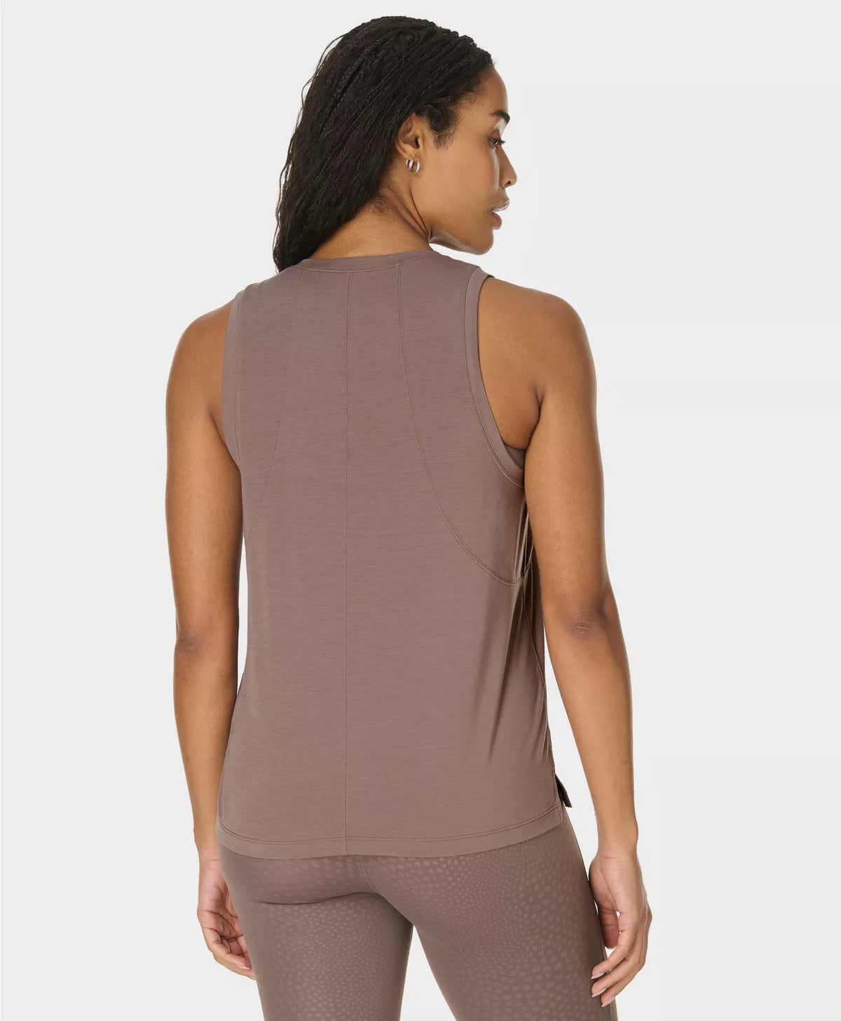 Woman wearing a brown sleeveless top and leggings on a white background