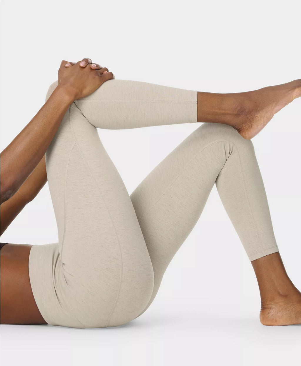 Beige leggings worn by a person sitting on a white background