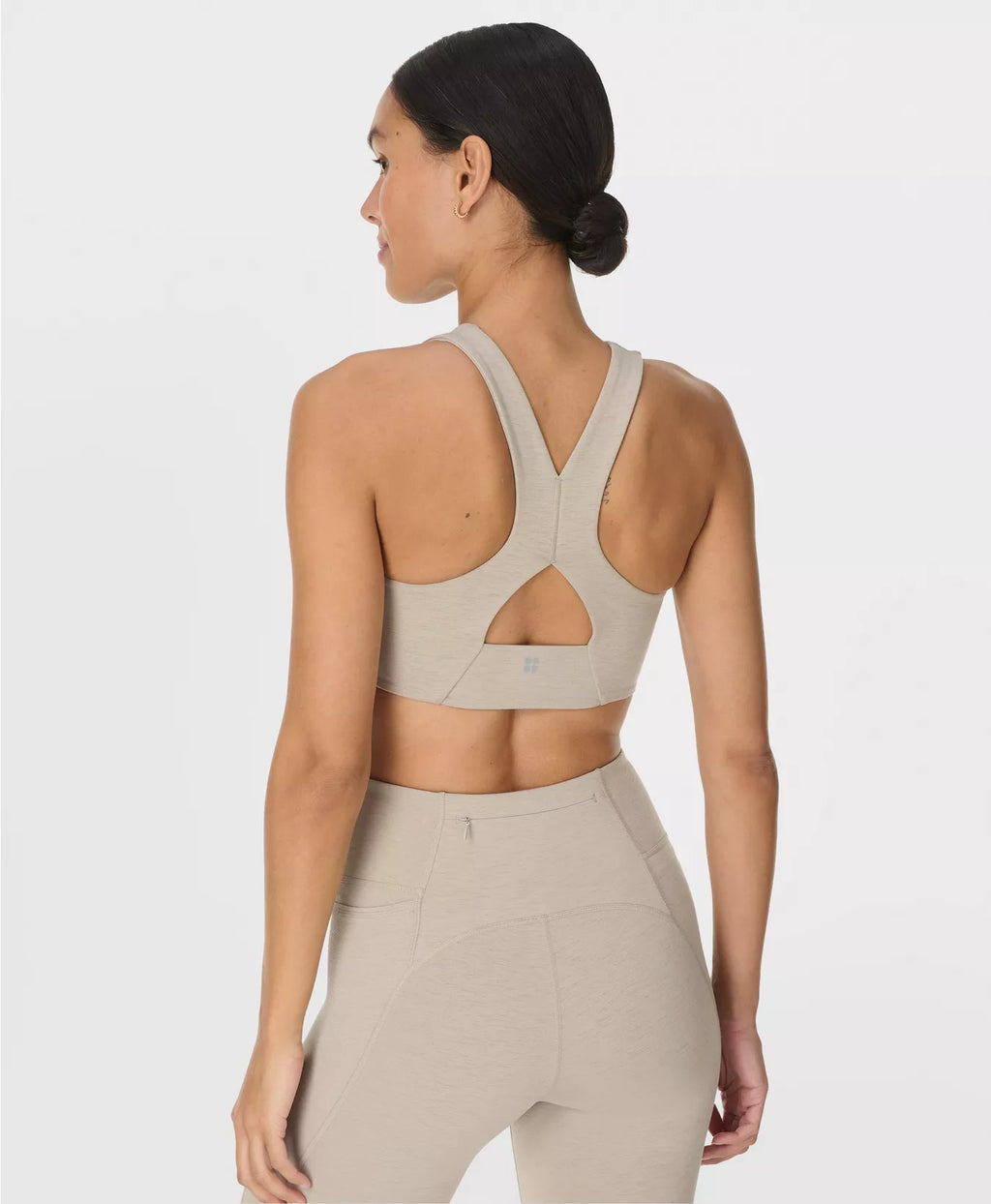 Woman wearing a beige sports bra and leggings on a white background