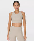 Woman wearing a beige sports bra and leggings on a white background