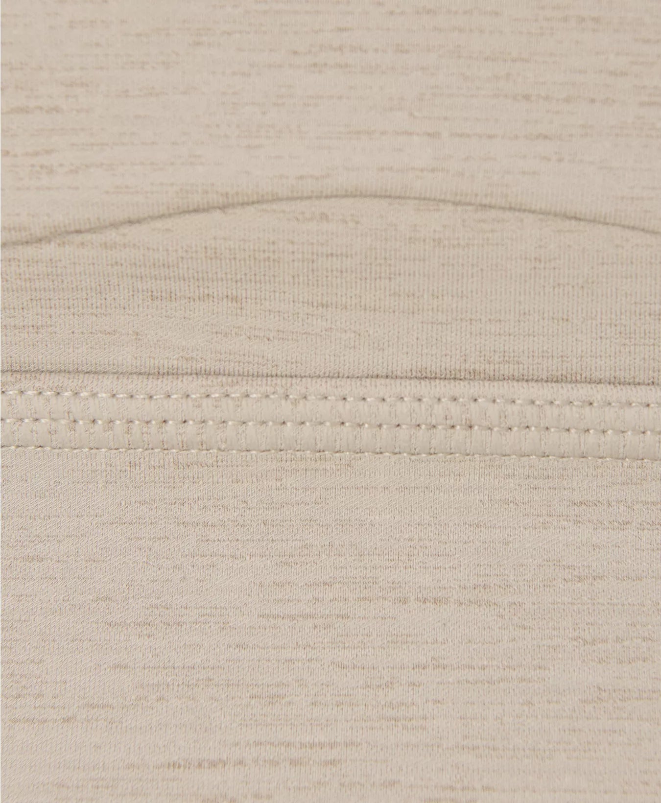 Close-up of beige fabric with a subtle pattern and stitching detail.