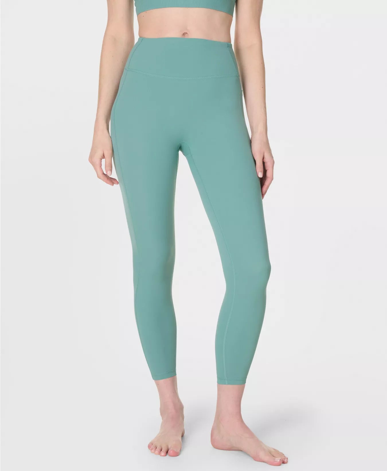 Person wearing teal leggings on a white background