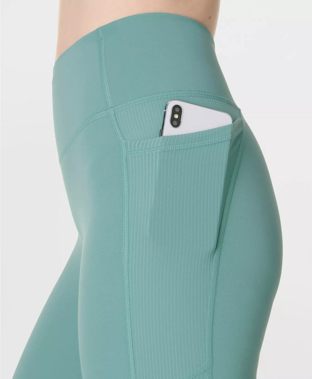 Teal leggings with a pocket holding a phone on a white background