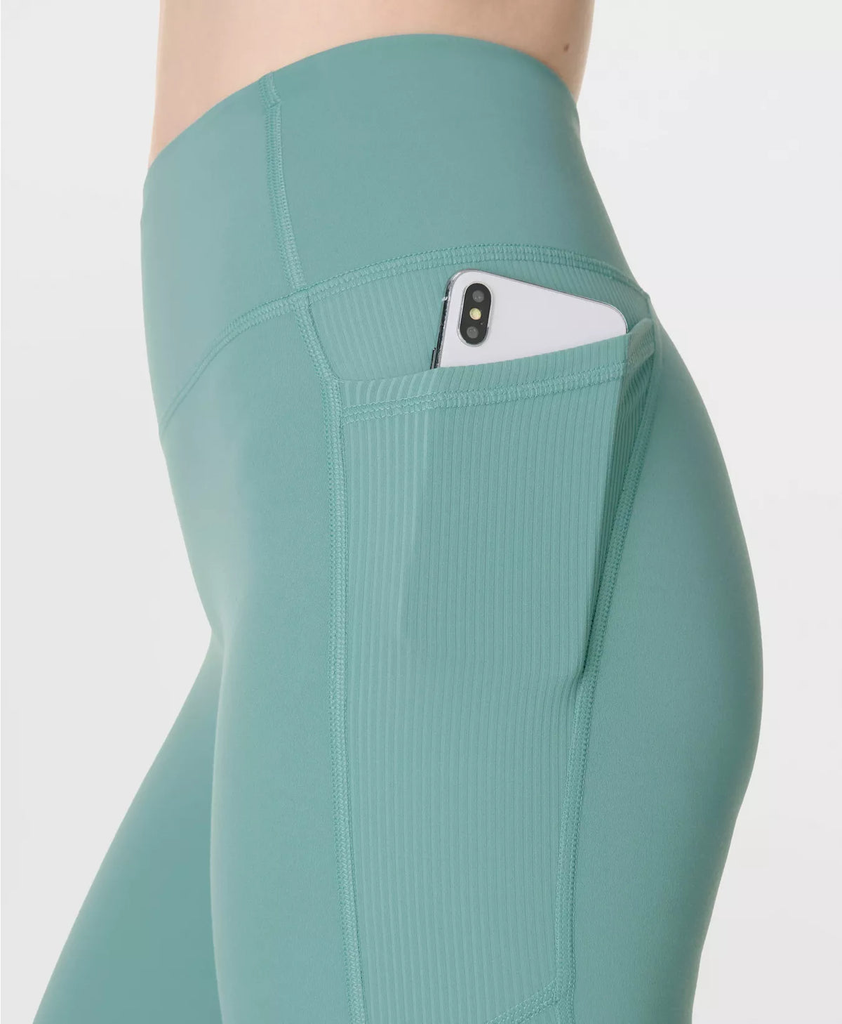 Teal leggings with a pocket holding a phone on a white background