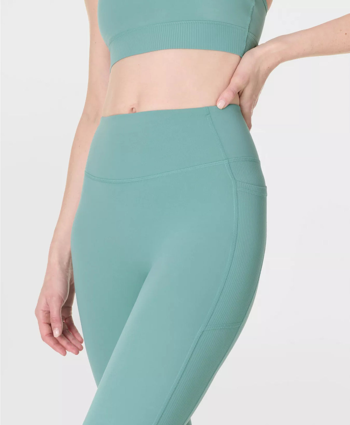 Teal athletic leggings worn by a person on a white background