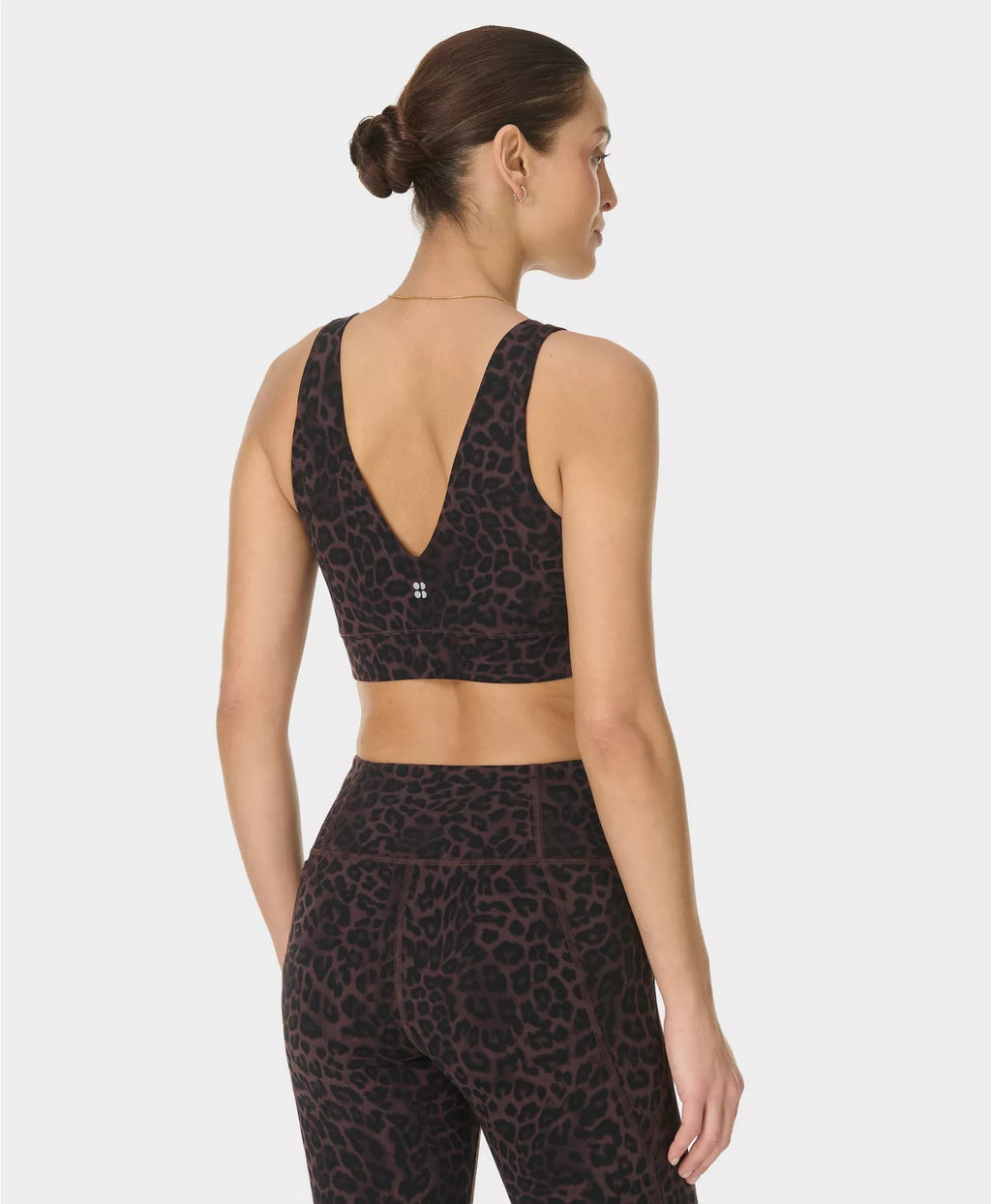 Woman wearing a black leopard print sports bra and leggings on a white background