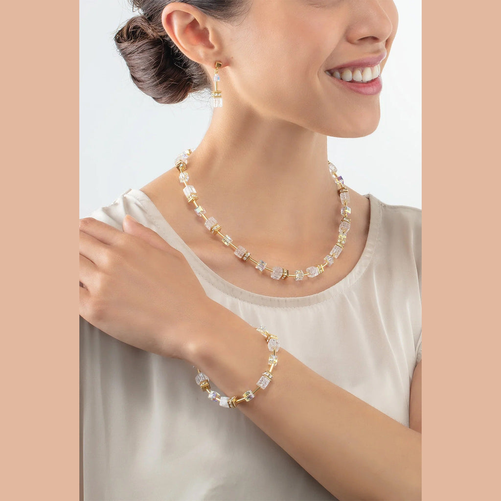 Woman wearing GeoCube Rock Crystal earrings, necklace, and bracelet jewelry set, gold plated.