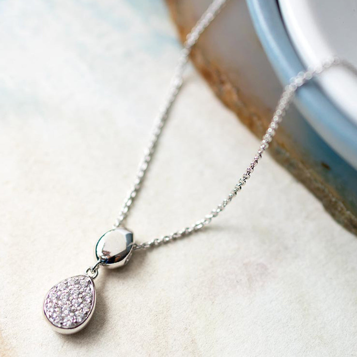 Close-up showcasing the Kit Heath silver necklace with double droplet pendant and pave CZ stones, stylish jewelry detail.