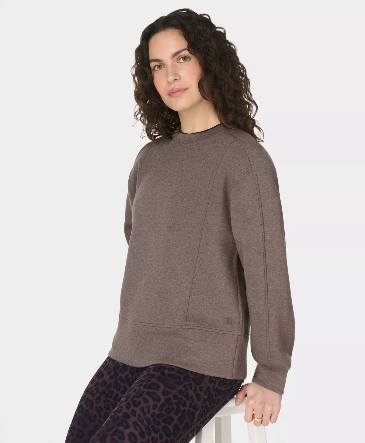 Woman wearing a brown sweatshirt and leopard print pants on a white background