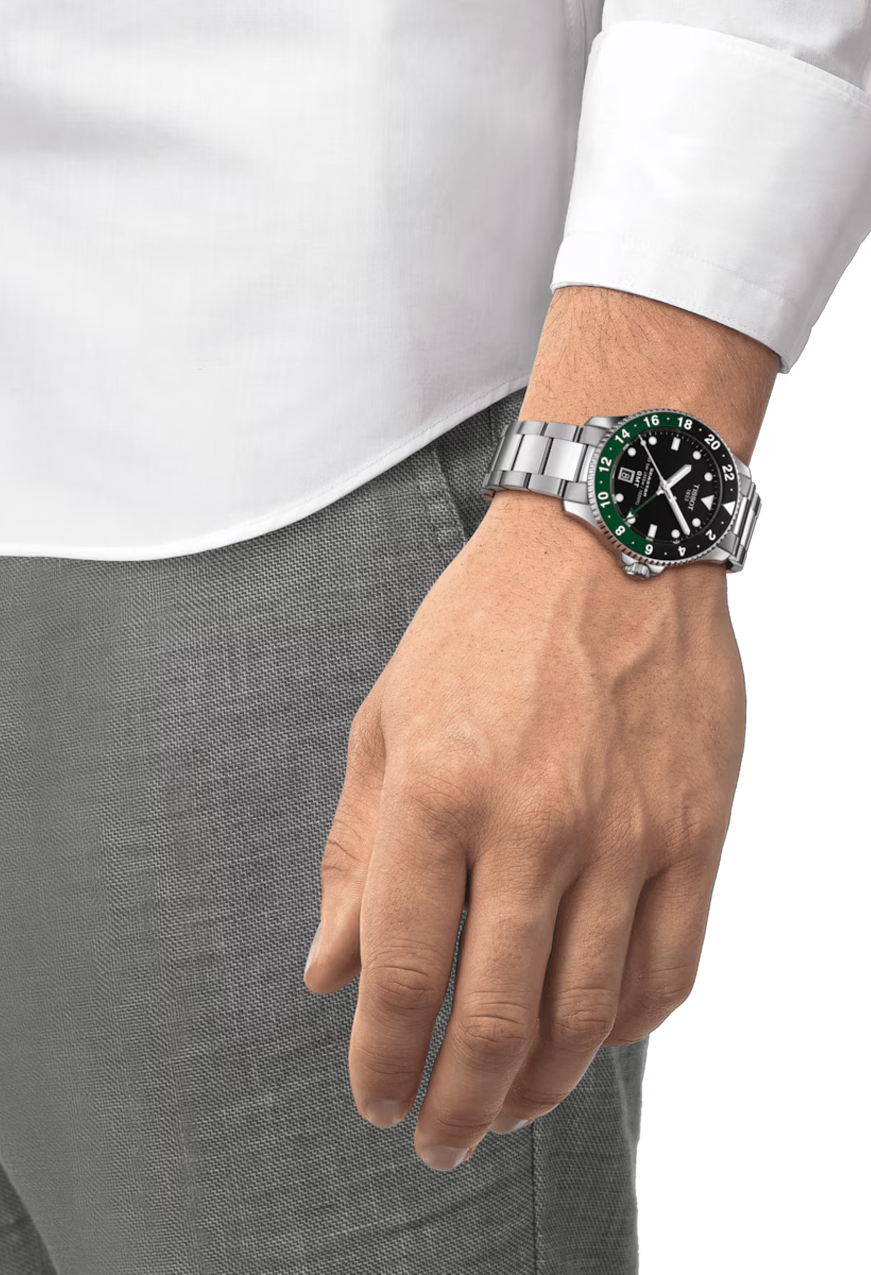 Man's wrist showcasing the Tissot Seastar 1000 GMT watch with stainless steel bracelet.
