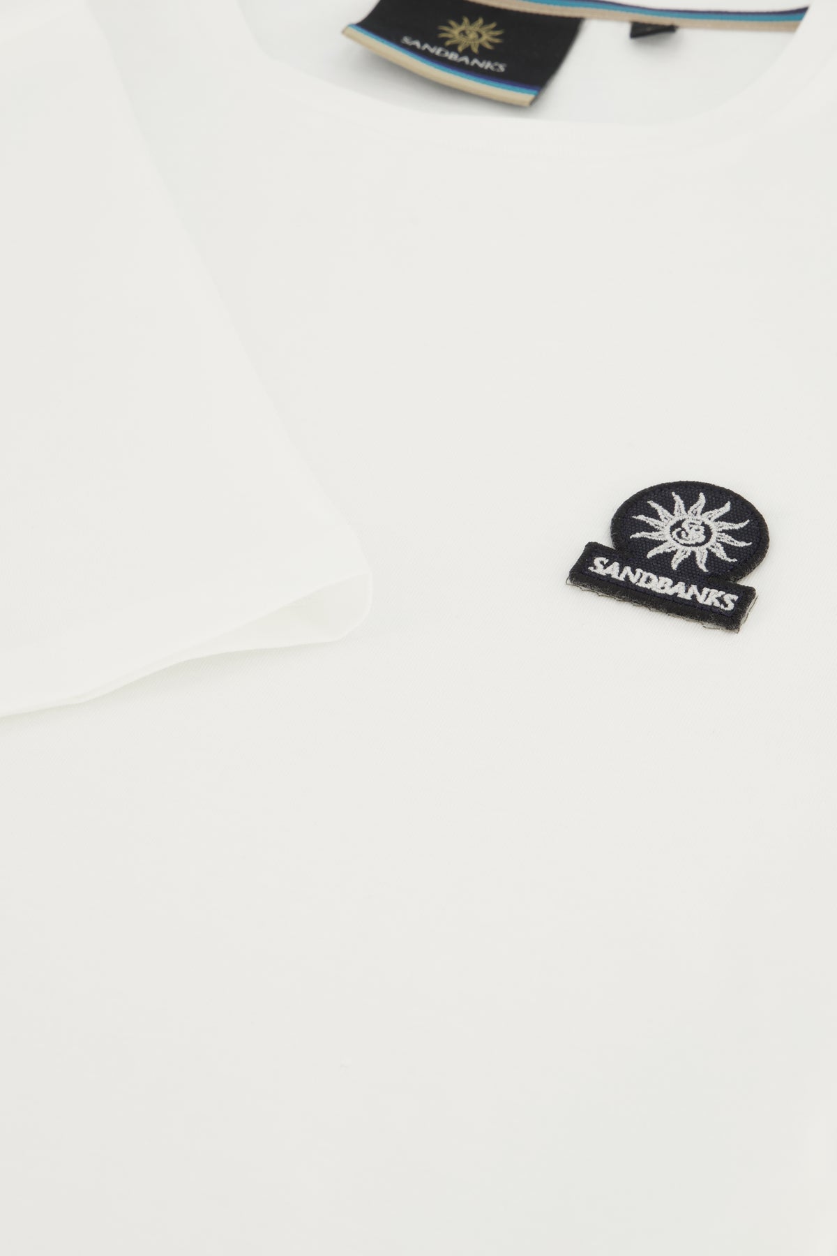 Close up image of Sandbanks logo on white t-shirt